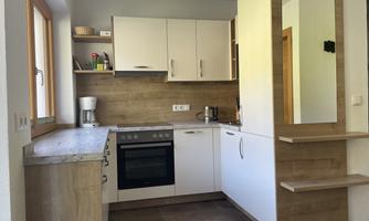 A modern kitchen with white cabinets and wooden shelves. It is bright and functionally designed.