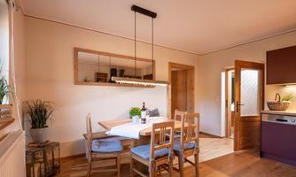 A cozy dining area with a wooden table and chairs. The warm colors and plants create an inviting atmosphere.