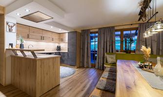 A modern kitchen with wood surfaces and an inviting dining area. Large windows let in plenty of light and create a cozy atmosphere.