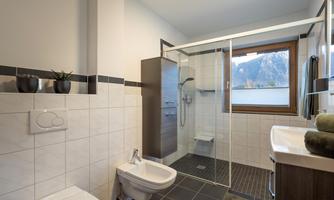 A modern bathroom with a shower and a window with mountain views. It is bright and well-equipped with elegant furniture.