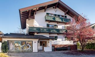 A beautiful, traditional house with balconies and a colorful facade. In front of the building stands a nice tree with red leaves. Ample parking is available. Garage space available upon request and for a fee.