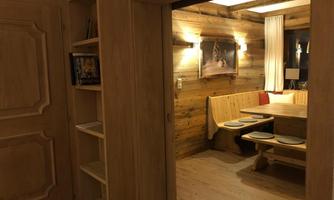 A cozy dining area with wooden furniture and soft lighting. The walls are clad in wood, creating a warm atmosphere.