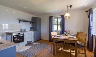 A modern and bright dining room with a wooden table and chairs. The kitchen is well-equipped and offers plenty of space.