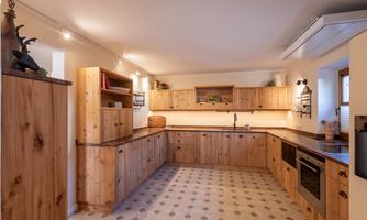 A modern kitchen made of wood with bright cabinets and a spacious countertop. The floor is designed with light tiles and a simple pattern.