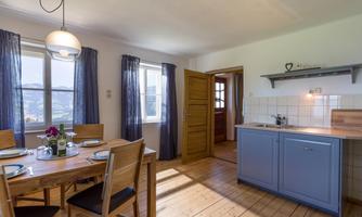 A cozy kitchen with a dining table and modern furniture. Large windows let in plenty of daylight and offer a beautiful view.
