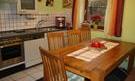 A cozy kitchen with a wooden cupboard and table. The table is set and has a beautiful decoration.