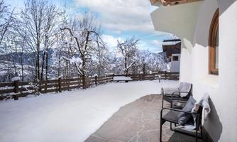 A beautiful winter garden with a snow-covered terrace. In the background, snow-covered trees and mountains are visible.