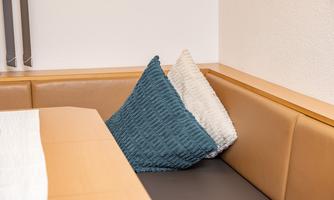 A cozy seating area with a padded bench and two cushions in blue and white. The wooden surface adds a warm atmosphere to the room.