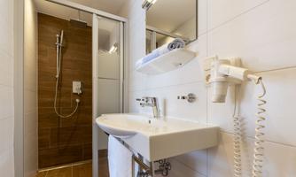 A modern bathroom with a shower and a sink. The walls are bright, and the decor is simple and functional.