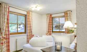 A cozy bedroom with light curtains and a large window. There is a comfortable bed and a floor lamp that create an inviting atmosphere.