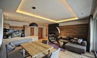 A modern living room with an open kitchen. The decor is stylish and cozy, with wood and neutral tones.