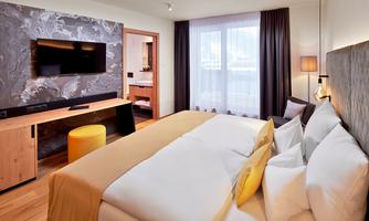A modern bedroom with a large bed and cozy pillows. The room has a stylish decoration and a window with plenty of natural light.