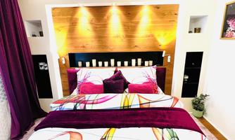 A cozy bedroom with colorful bedding and pillows. The walls are painted in soft tones, and there is decorative lighting.