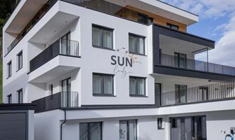 A modern building with several floors and balconies. The facade features the inscription "SUN lodge".