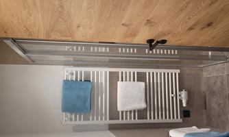 A modern bathroom with a shower, a towel rack, and wooden details. There are bright colors and a clean, inviting atmosphere.