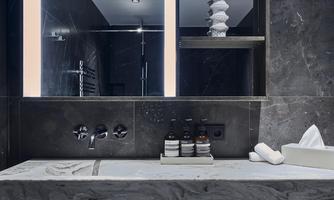 A modern bathroom with an elegant marble vanity. The mirror has integrated lighting, and personal care products are placed on the shelf.