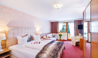 A comfortable hotel room with two beds and modern furniture. The decoration includes fresh flowers and a cozy atmosphere.