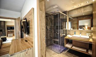 A modern bathroom with a glass shower enclosure and an elegant sink. Wood and stone accents create a cozy atmosphere.