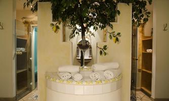 An elegant spa area with a central tree and neatly folded towels. The walls are bright and the furnishings appear inviting and relaxing.