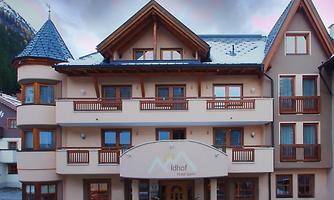 A charming hotel with an inviting entrance and traditional wood decorations. It is located in a picturesque setting with mountains in the background.