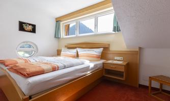 A cozy bedroom with a double bed and colorful bedding. Large windows provide plenty of daylight and beautiful views.