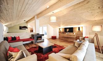 A modern living room with a wooden ceiling and cozy furnishings. There is an open atmosphere, with a central table and a fireplace.