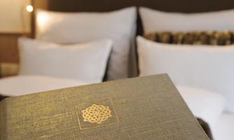An elegant room with comfortable pillows and a textbook in the foreground. The calm atmosphere invites relaxation.