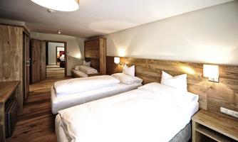 A modern hotel room with two single beds and wood paneling. There is a table and a cozy atmosphere.