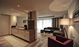 A modern apartment with an open kitchen and a cozy living area. Large windows let in plenty of natural light and create an inviting atmosphere.