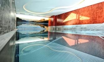 An elegant indoor pool with modern design and reflective water. The walls are adorned with an impressive landscape graphic.