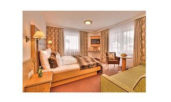 A cozy hotel room with a single bed, a table, and a chair. Large windows provide plenty of daylight and an inviting atmosphere.