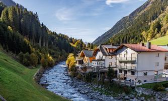 A picturesque valley with green meadows and a clear river. In the background, majestic mountains and forests rise up.