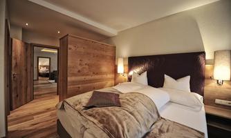 A cozy bedroom with a comfortable bed and modern wooden details. The room is designed elegantly and invitingly, ideal for relaxation.