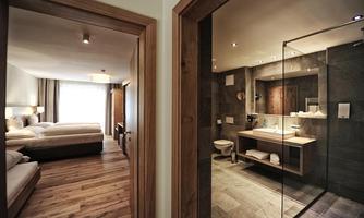 A modern hotel room with two beds and an elegant bathroom next to it. The decor is stylish and inviting.