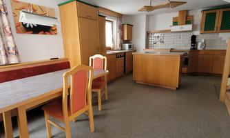 A cozy kitchen with wooden furniture and a dining area. The room is bright and feels welcoming.