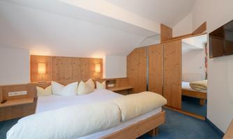 A cozy bedroom with wooden furniture. There is a large bed and a mirror that create an inviting atmosphere.