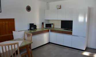 A modern kitchen with white cabinets and a small dining table. The room is designed to be bright and welcoming.