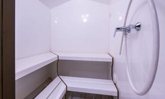 A modern shower area with white walls and simple shelves. The furnishings are designed to be minimalist and clean.