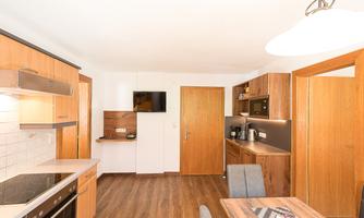 A modern kitchen with wooden cabinets and a bright, inviting atmosphere. There is a dining area and modern appliances.