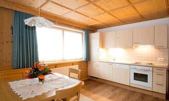 A bright and inviting kitchen with a dining area. Large windows and wood paneling create a cozy atmosphere.