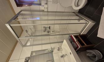 A modern bathroom with a shower and a sink. There is also a toilet and a mirror.