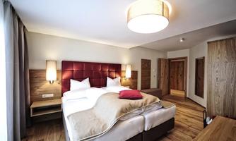 A modern bedroom with a large double bed and elegant wooden furniture. Soft lighting creates a cozy atmosphere.