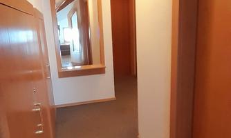 A bright hallway with wooden details and a mirrored wall. Doors lead to various rooms.
