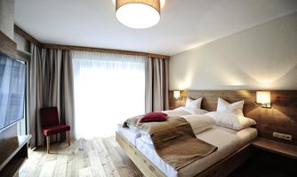 A modern bedroom with a double bed and wooden details. A window provides plenty of natural light and the room is designed simply and elegantly.