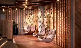 A modern room with hanging swings and rustic wood paneling. The warm lights create a cozy atmosphere.