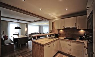 Modern kitchen with wood and white tones. An inviting dining area is visible in the background.