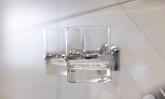 Two clear glasses on a wall bracket with a modern surface. The glasses are empty and ready for a drink.