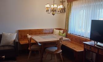 A cozy living space with wooden furniture and a dining table.  
Large windows provide plenty of daylight and an inviting atmosphere.