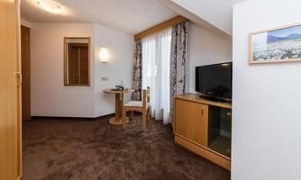 A cozy room with a table, a chair, and a television. Bright colors and a carpet create an inviting atmosphere.