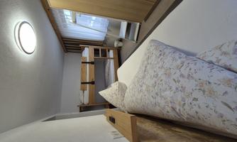 A simple room with a double bed and a bunk bed. The room is bright and has a large wardrobe.